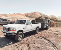 a white pickup truck parked on top of a dirt field