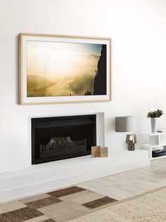 a living room with a fireplace and pictures hanging on the wall above it's mantle