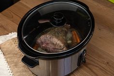 a slow cooker filled with food on top of a wooden table