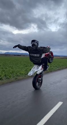 a person riding a motorcycle on the road with their arms in the air and one hand out