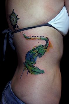 a woman's stomach with a tattoo on it that has an image of a lizard