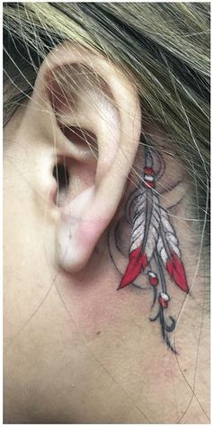 a woman's behind the ear with a red and white feather tattoo