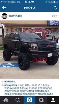 a black truck parked in front of a building with the words chevrolet written on it