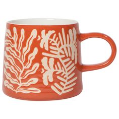 an orange and white mug with leaves on it