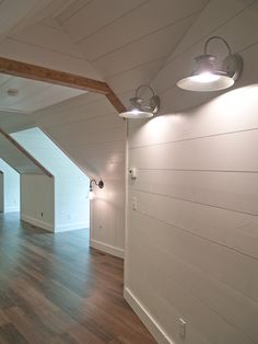 an empty room with wooden floors and white walls, along with two lights on either side of the wall