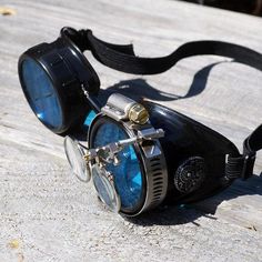 Steampunk Goggles from the fractured mind of H.G. Brasswell. Our goggles are perfect for Gifts, Cosplay, Halloween costume, or eye protection from sandstorms. If you need eye protection, we've got you covered. I present to you, a wonderful pair of black steampunk optic-conductor goggles with blue lenses, silver accents and a pair of magnifying loupes (3.3x and 5x) and a SOLID BLACK elastic headstrap. This fantastical pair of goggles is perfect for any airship captain, mad scientist, wasteland wa Adjustable Blue Costume Accessories For Halloween, Adjustable Blue Costume Accessories For Cosplay, Airship Captain, Steampunk Watches, Black Steampunk, Goggles Glasses, Steampunk Goggles, Steampunk Watch, Steampunk Lamp