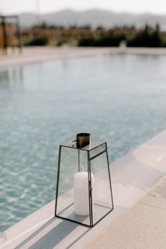 a candle that is sitting on the side of a swimming pool with water in it