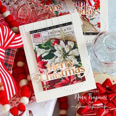 a christmas card with poinsettis and ribbon around it on top of other cards