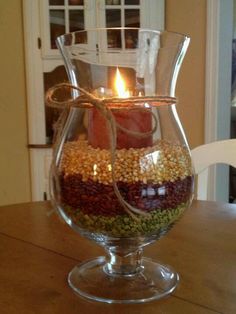 a candle that is inside of a glass vase filled with food on a wooden table