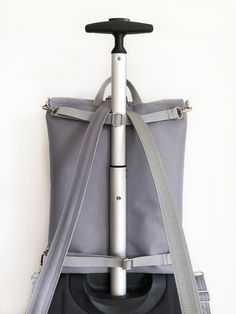 an umbrella is attached to the back of a gray bag with grey straps on it