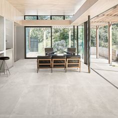 an empty living room with two chairs and a table in front of glass doors that look out onto the outdoors