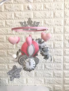 a pink and silver mobile with hearts, crowns, and other decorations