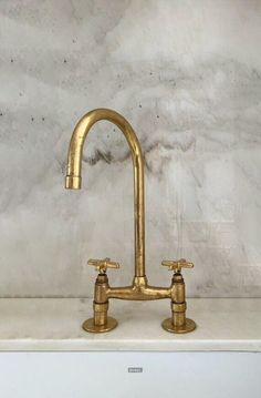 a gold faucet sitting on top of a white counter