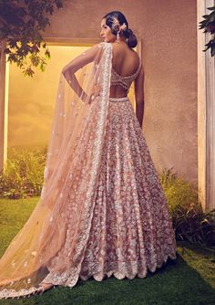 Editors Note Dazzle in pale blush with this organza lehenga, meticulously adorned by hand with intricate foliage motifs using ornamental luster sequences and beads. Paired effortlessly with a matching blouse and scalloped dupatta enhanced by crystal drops, this ensemble exudes modern elegance and sophistication. Floral Bridal Lehenga, Desi Dress, Bridal Makeup Images, Organza Lehenga, Indian Wedding Outfit, Padded Blouse, Beads Work, Embroidered Lehenga