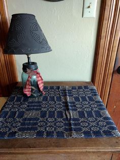 a lamp sitting on top of a wooden table next to a blue and white blanket