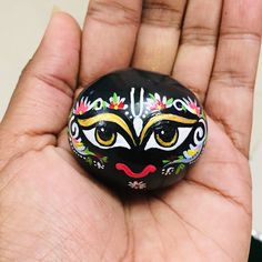 a hand holding a painted rock in the palm