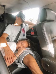 a woman sleeping in the back seat of a car with a man sitting next to her