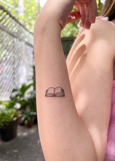 a woman's arm with a book tattoo on the left side of her arm