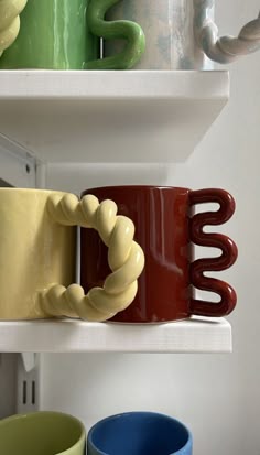 two mugs are sitting on the shelf next to each other, one is shaped like a snake