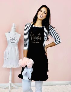 a woman standing next to a mannequin wearing an apron and holding a flower