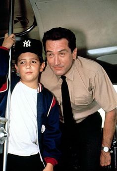 a man standing next to a young boy on top of an airplane with his arm around him