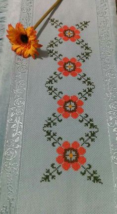 a cross - stitch table runner with flowers on it and a yellow flower in the middle