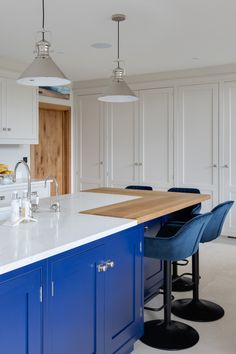 a kitchen with blue stools and white counter tops in front of a large island