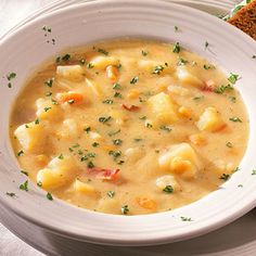 a white bowl filled with soup next to a slice of bread