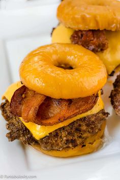 two bacon, egg and cheese burgers on a plate with donuts in the background