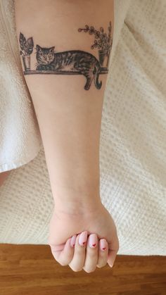 a woman's foot with a cat tattoo on her left leg and an armband