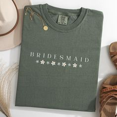 the bridesmaid t - shirt is next to her shoes and hat on the table