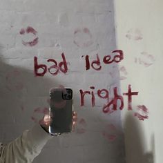 a person holding up a cell phone in front of a wall with writing on it