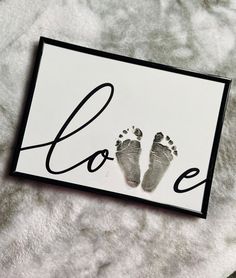 a baby's hand and foot prints are displayed on a white sheet with the word love written across it