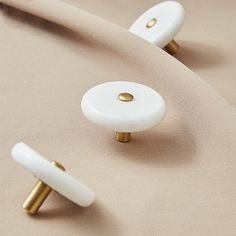 two white and gold knobs on a beige cloth