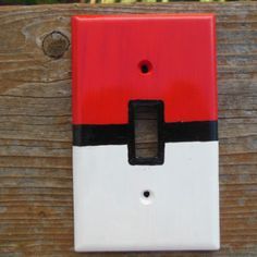 a red and white light switch sitting on top of a wooden fence