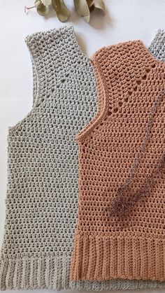 three knitted vests sitting next to each other on top of a white table