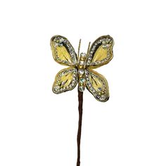 a yellow and white butterfly on a stick with crystal stones in its wings, sitting on top of a table