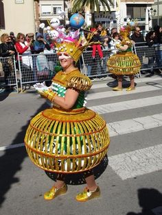 some people are walking down the street in elaborately decorated costumes and headgear