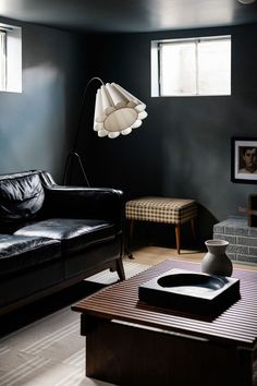 a living room with black walls and leather furniture