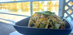 a blue bowl filled with food sitting on top of a table next to a lake