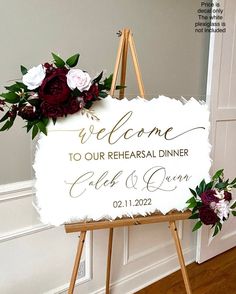 a welcome sign with flowers on it in front of a door that says, welcome to our rehearsal dinner