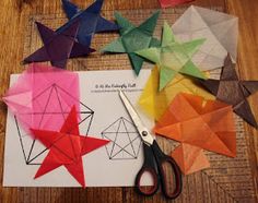 several different colored origami stars and scissors on top of a piece of paper