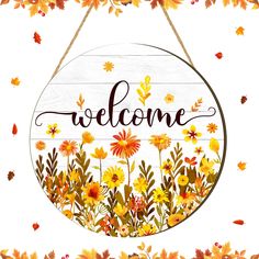 a welcome sign hanging from the side of a wooden frame with fall leaves around it