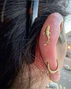 a close up of a persons ear with a gold lizard on it's side