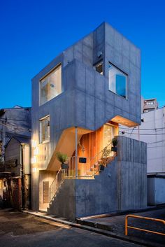 a concrete house with stairs leading up to the second floor and windows on each side