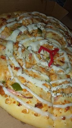 a pizza with white sauce and toppings in a box