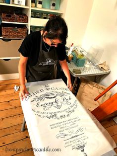 a woman in an apron is cutting up a large piece of paper on a table