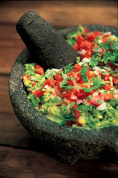 a bowl filled with guacamole on top of a wooden table