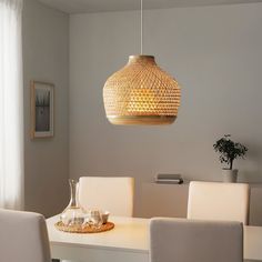 a dining room table with white chairs and a rattan light fixture