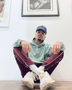 a man sitting on top of a wooden floor next to a wall with pictures on it